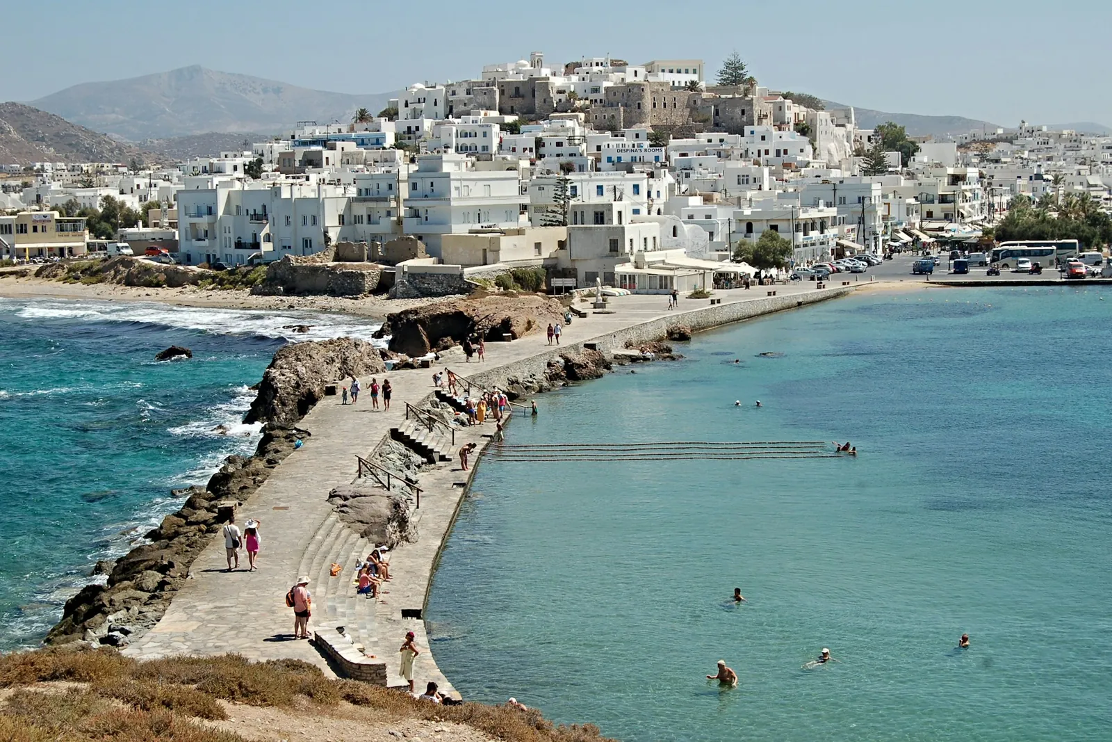 A whitewashed Cycladic town curving around a turquoise bay.